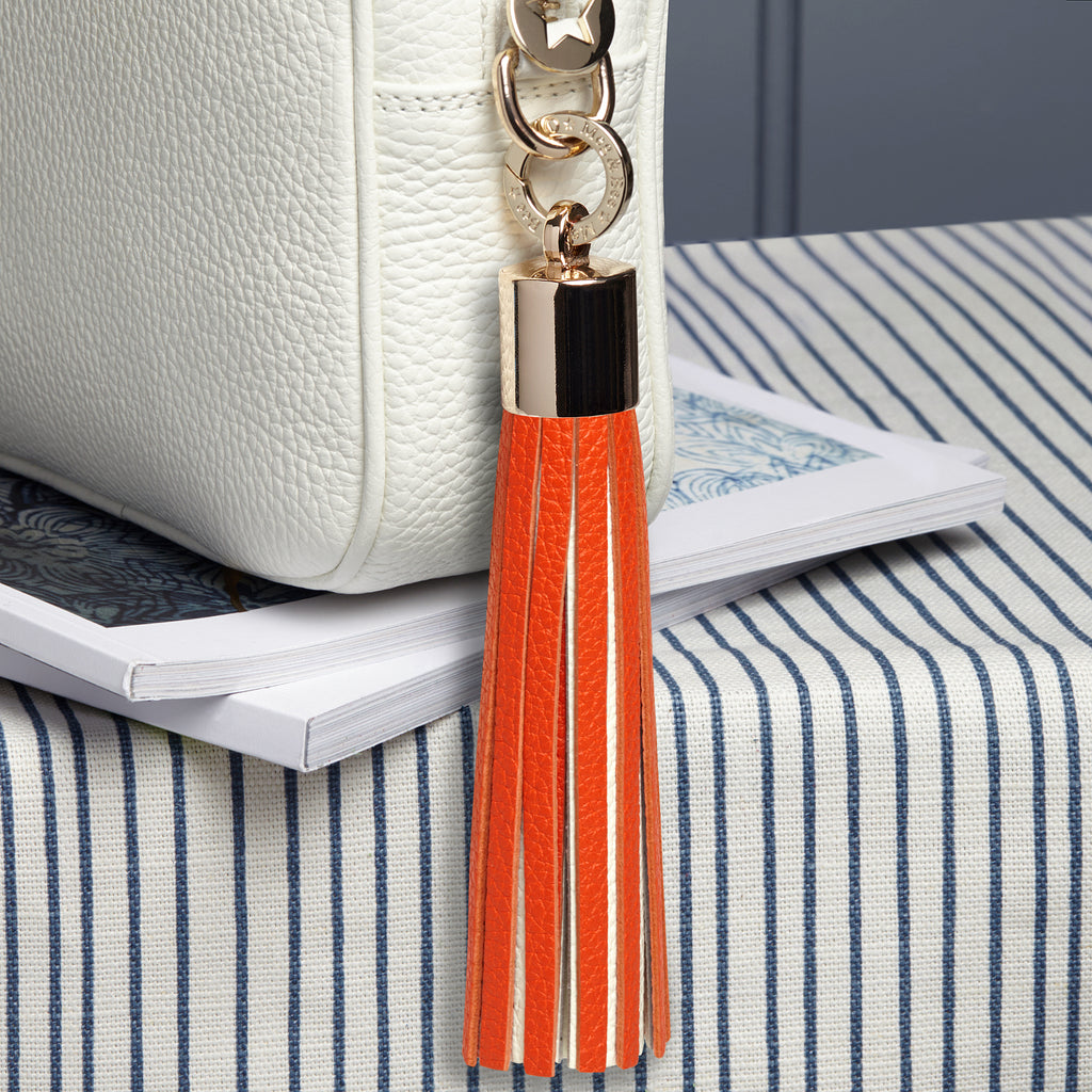 large leather orange and white removable bag tassel with gold hardware and attachable charm ring 