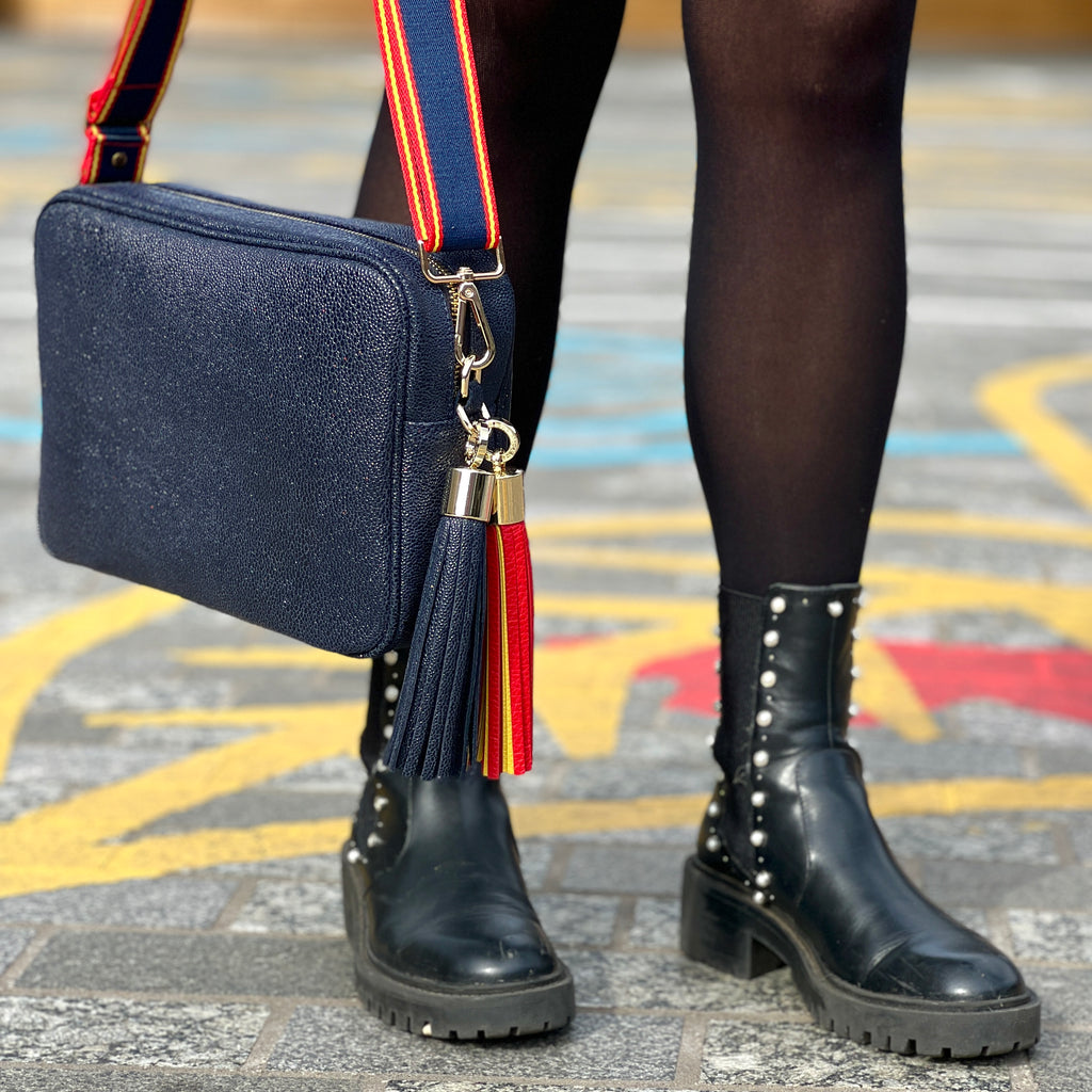 Large navy textured crossbody bag with removable matching large tassel and red and yellow tassel with slim navy, red and yellow interchangeable strap 