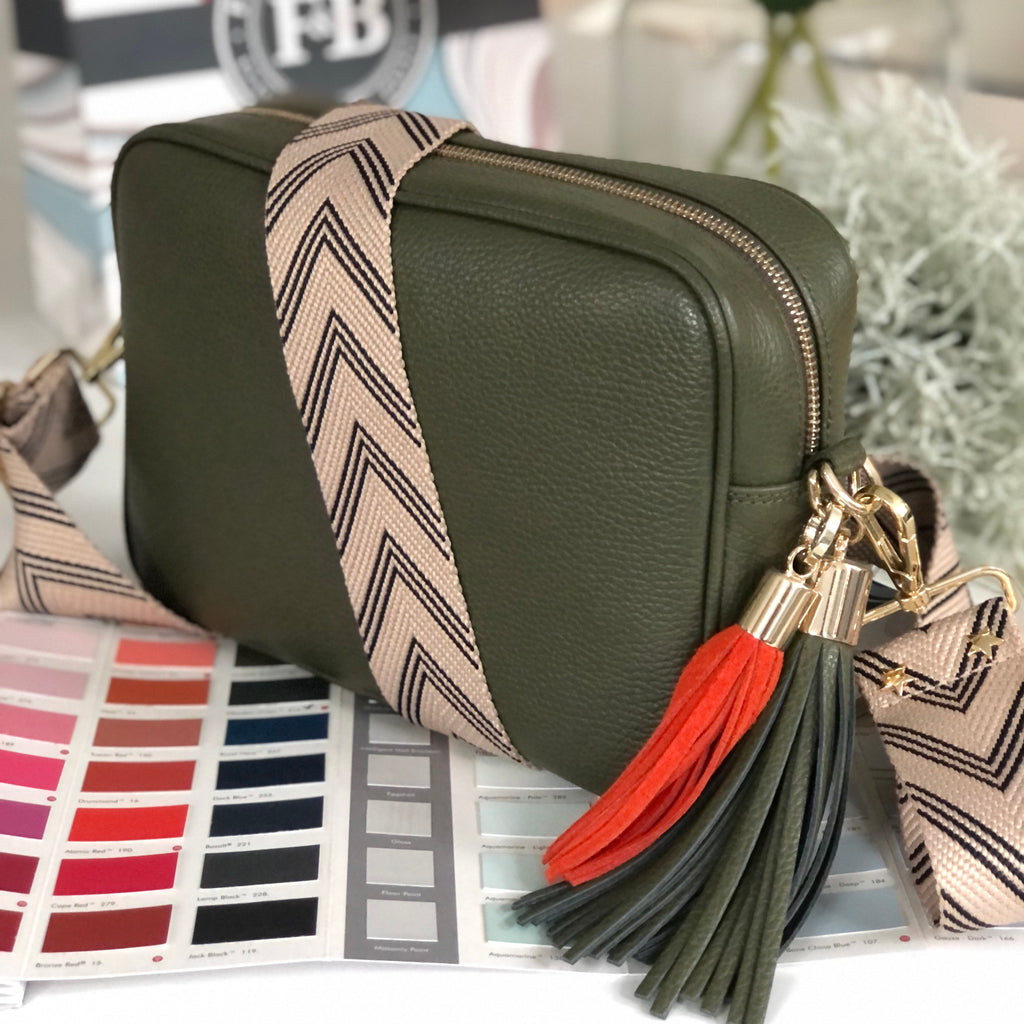 Large olive green crossbody bag with herringbone patterned wide strap and removable green and red tassel 