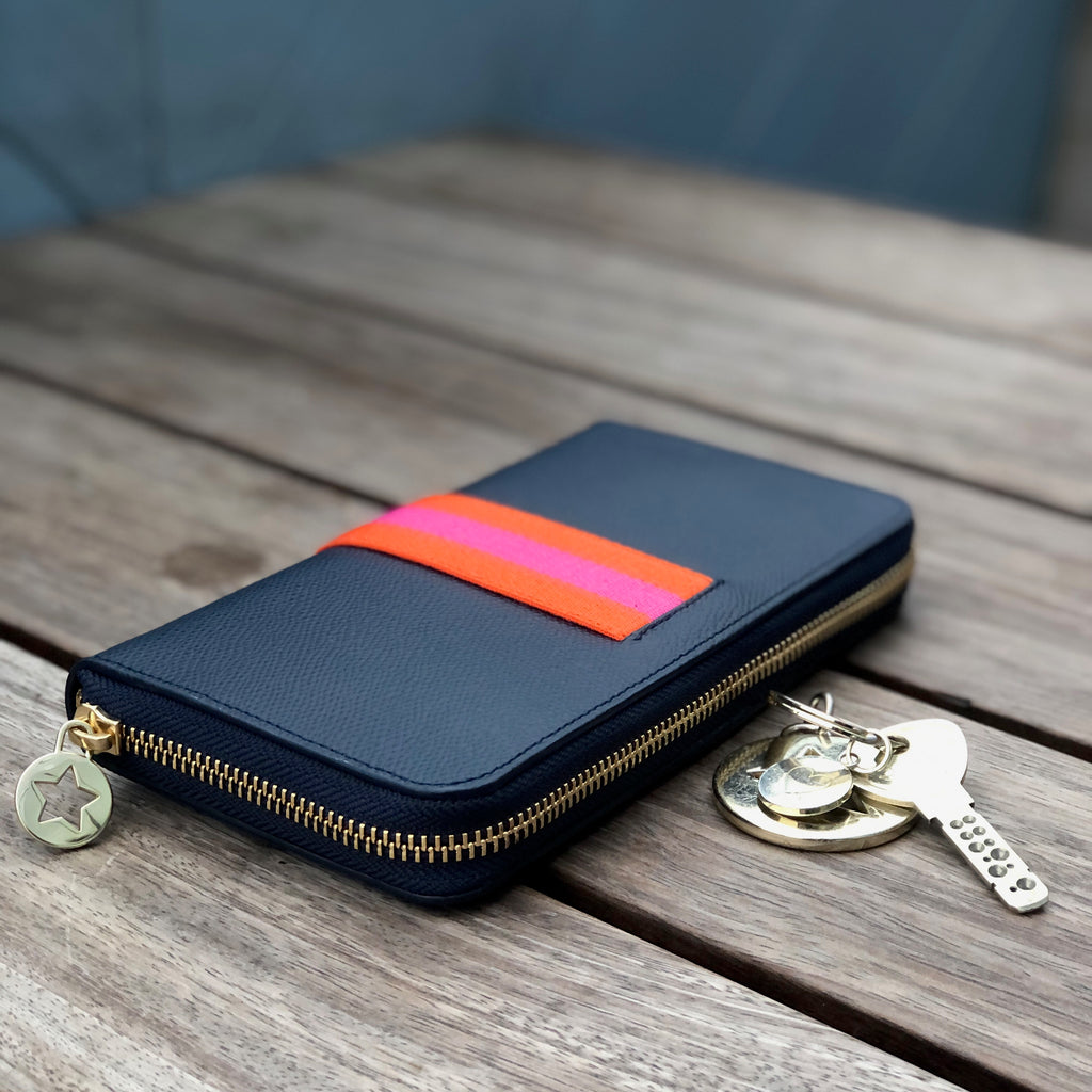 Large rectangular navy blue leather purse with orange and pink central webbing stripe with gold hardware