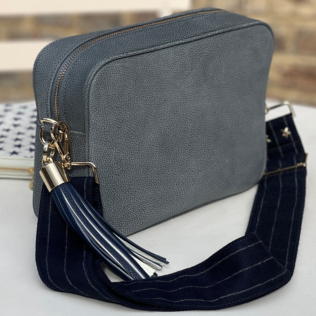Large suede grey crossbody bag with blue and white tassel and navy blue pin striped wide interchangeable fabric strap 