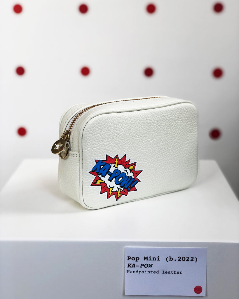 White small leather bag with graphic ka-pow design in the corner with gold hardware